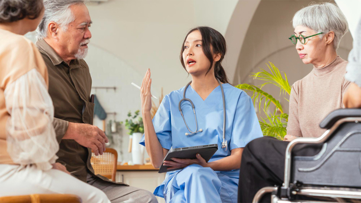 Young female doctor speaking to a group of elderly individuals.