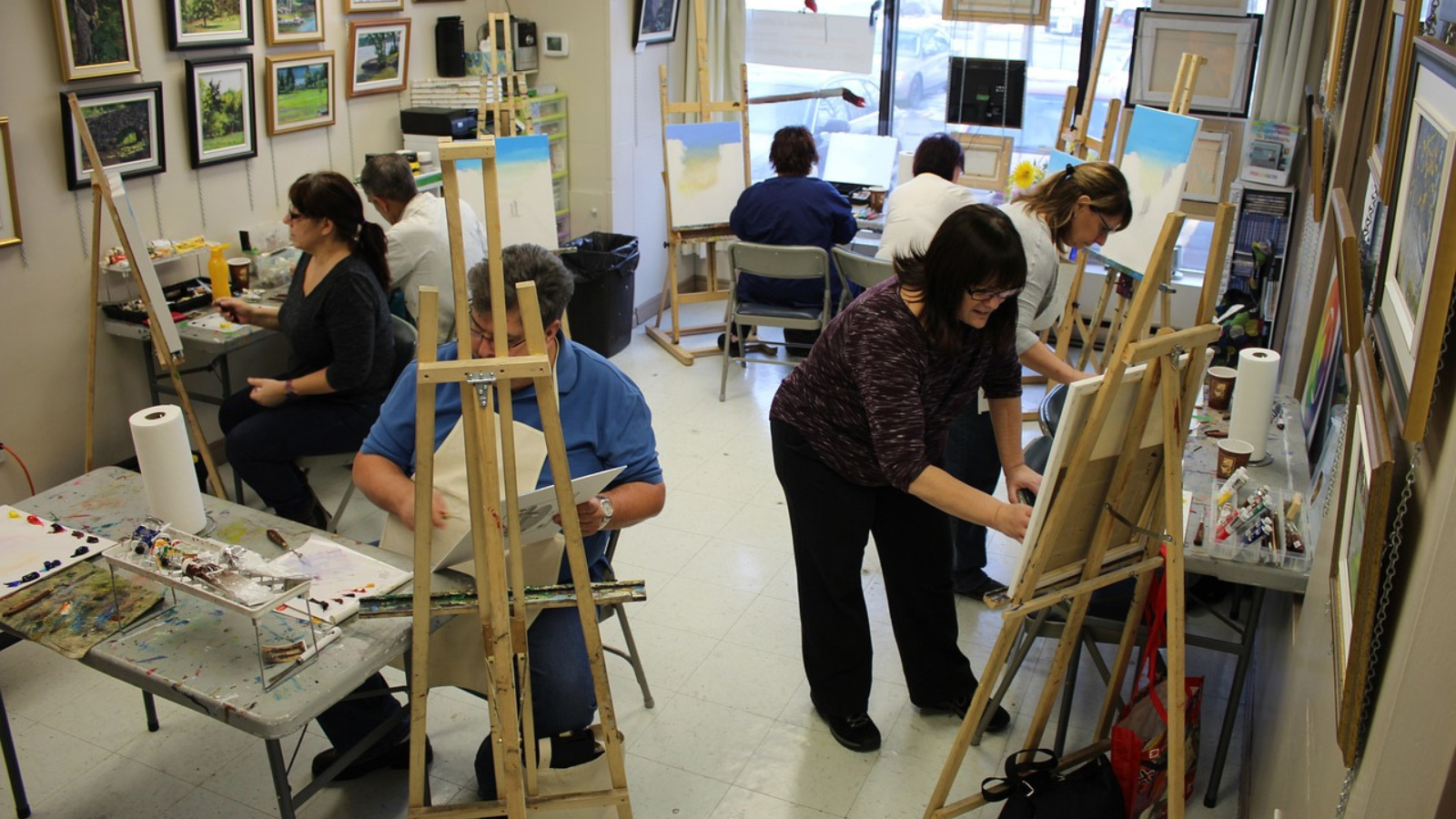Group of people in a room painting on canvases.